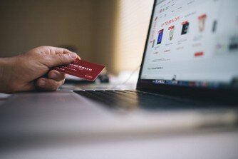 Aktuelle TÜV-Gebühren Person hält Bankkarte an Laptop